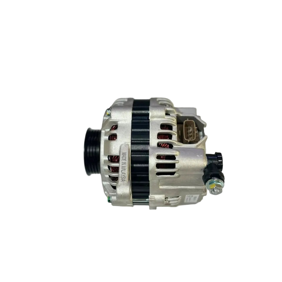 A silver and black automotive alternator photographed on a white surface with a blurred workshop background.