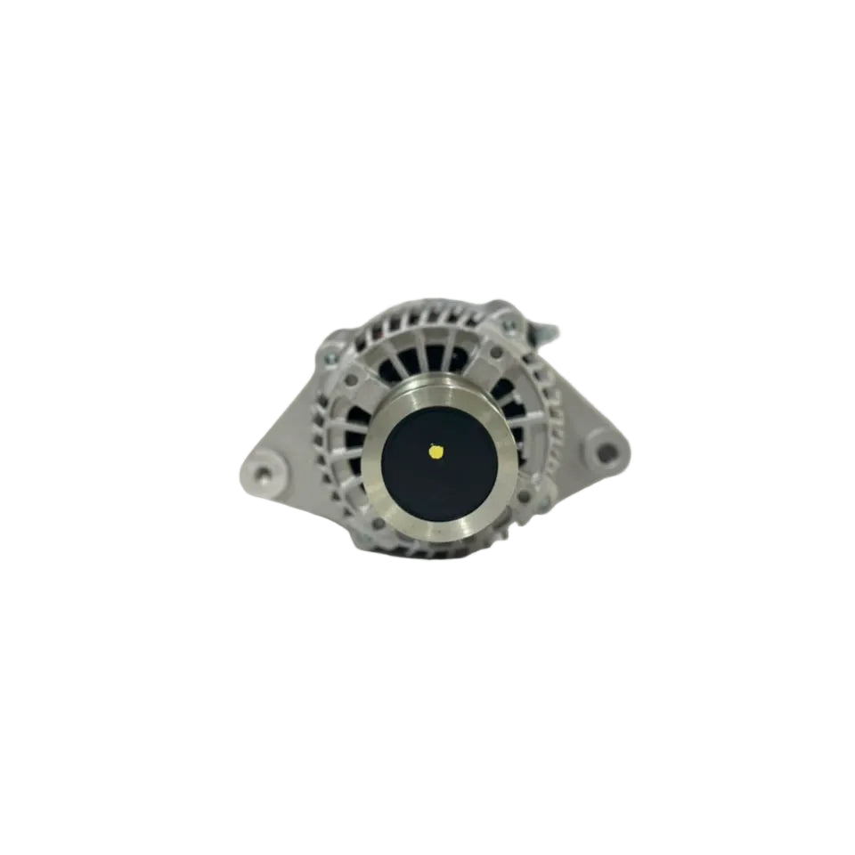 A silver metallic automotive alternator resting on a white surface with a blurred warehouse background.