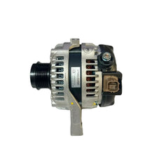 A used automotive alternator with a silver aluminum body, black ribbed pulley, and black electrical connector, resting on a white surface.