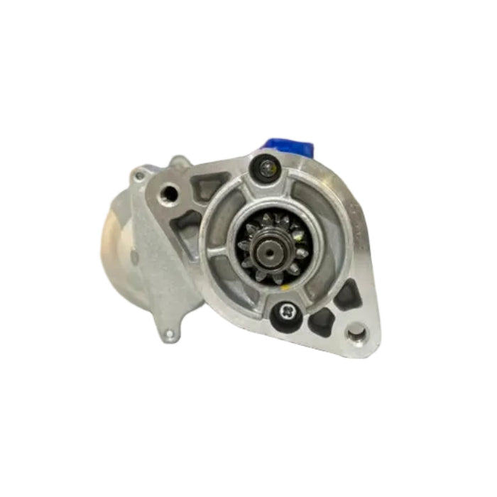 An automotive metal part, likely an alternator or starter motor, displayed on a white counter in a workshop with blurred shelves and a man in the background.