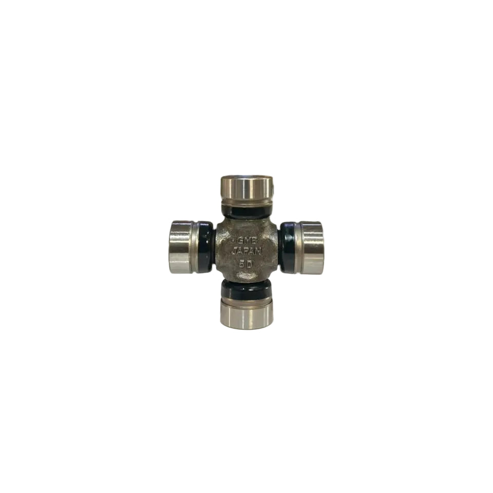 A small metal automotive component, likely a crossmember or knuckle bearing assembly, standing upright on a white surface with a blurred warehouse background.