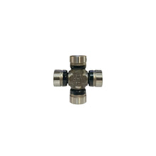 A small metal automotive component, likely a crossmember or knuckle bearing assembly, standing upright on a white surface with a blurred warehouse background.